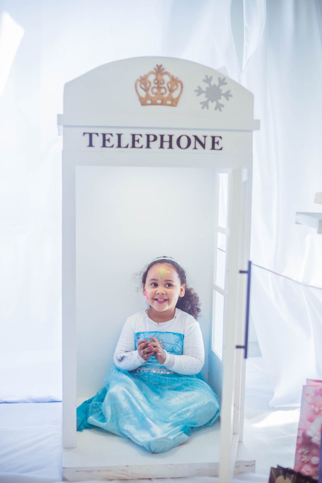A little guest in a Frozen dress sitting inside the Mini & Me photo booth