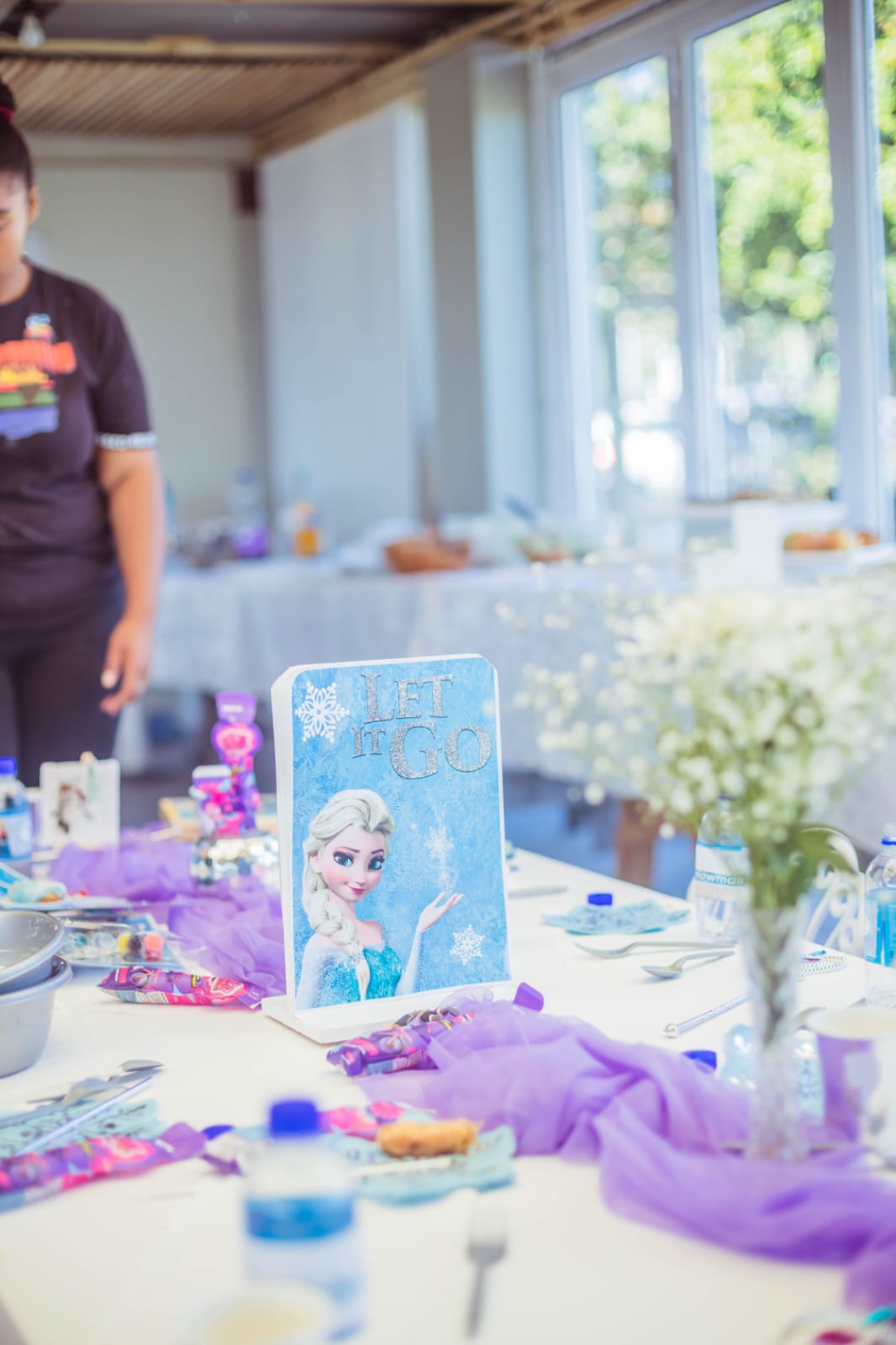 Party table decorated with purple runners and a Let It Go centrepiece