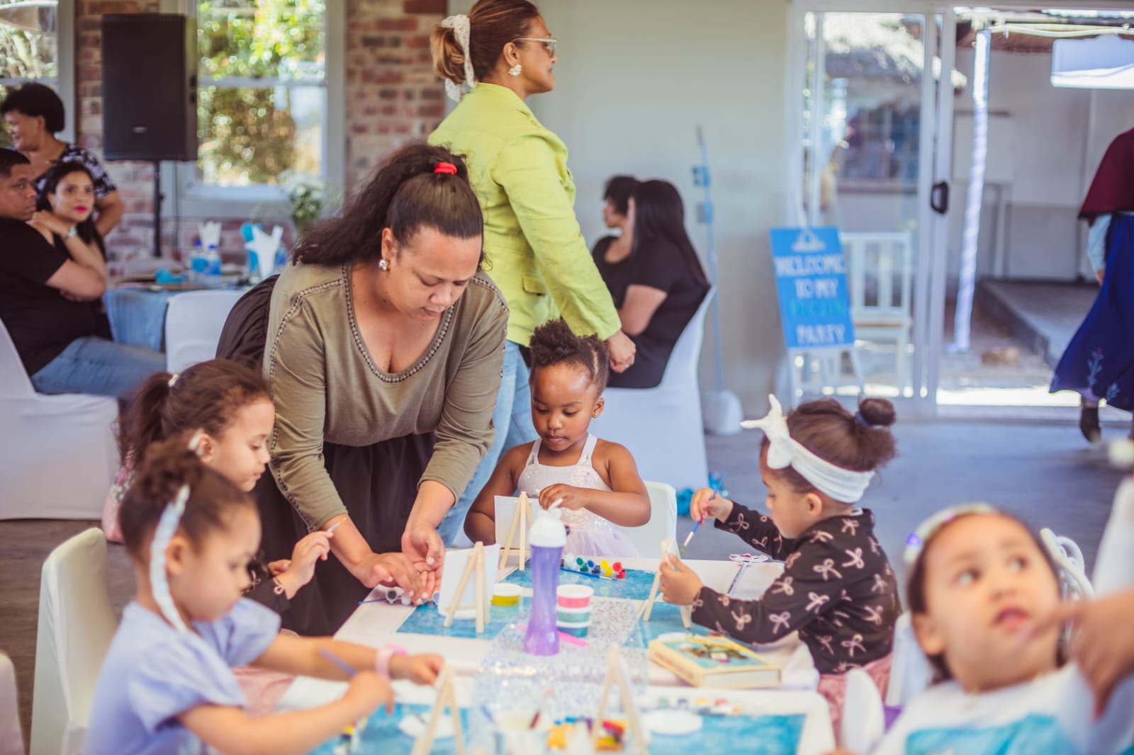 Little artists painting mini canvases at the Frozen party craft table